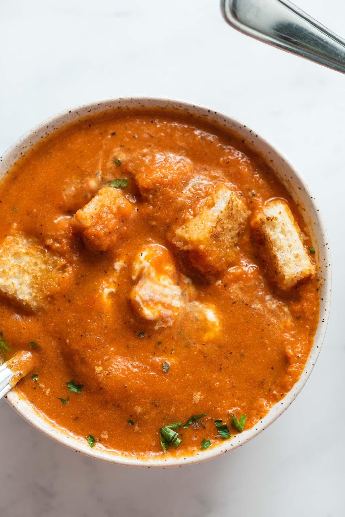 Geroosterde Rooipeper Tamatie Sop 2 Bowl of red pepper tomato soup topped with cubes of toasted bread.