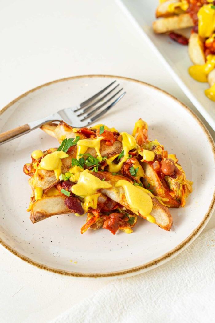 Veganes Chili Kaas Tjips 2 ’n Klein bordjie gebakte patatjies bedek met chili en kaassous.