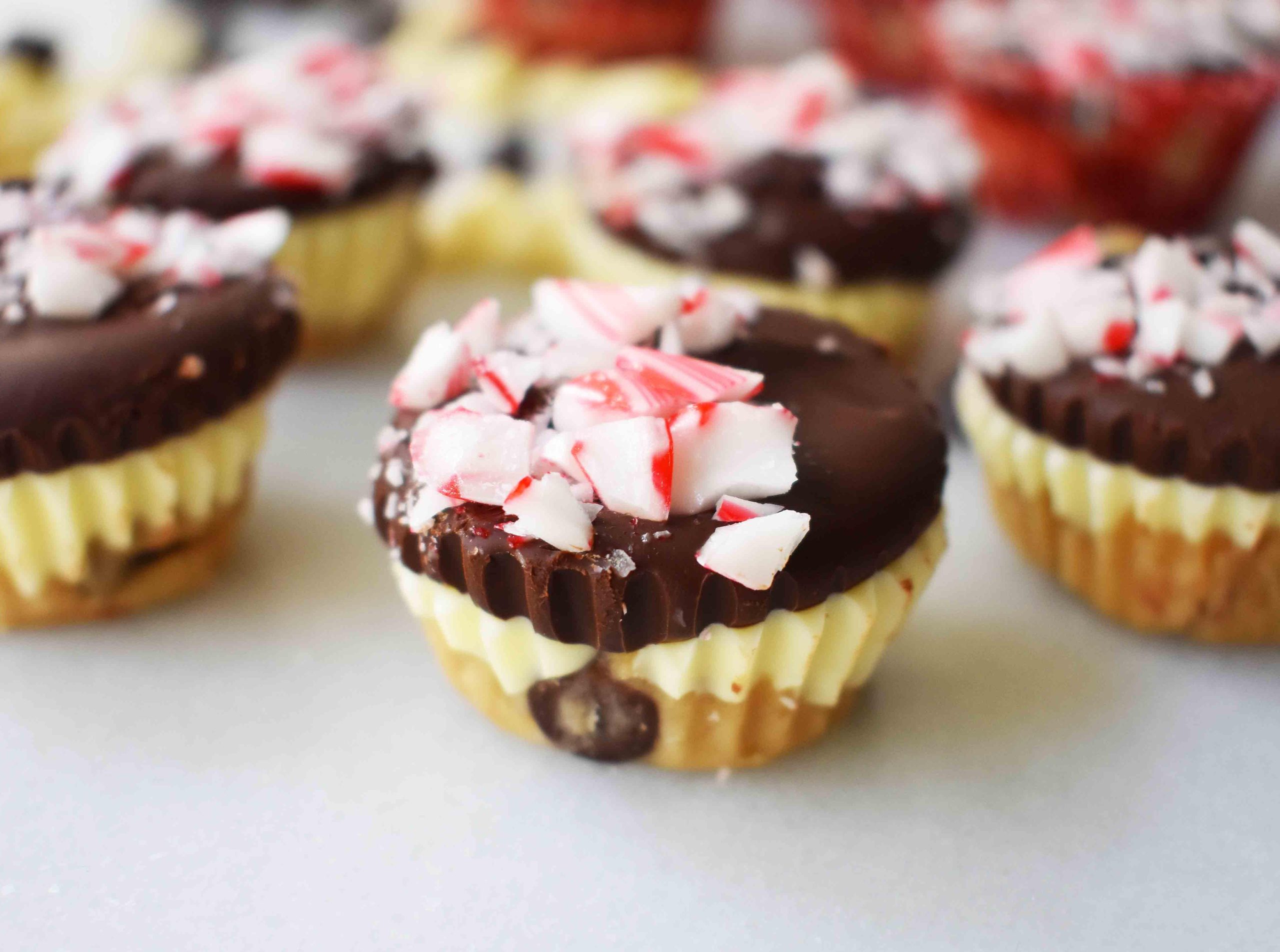 Κυπελλάκια Ζύμης Μπισκότου Peppermint Bark από το Modern Honey. Ζύμη μπισκότου με κομματάκια σοκολάτας χωρίς αυγά, στρωμένη με λευκή σοκολάτα και ημίγλυκη σοκολάτα, και γαρνιρισμένη με τριμμένα ζαχαρωτά μπαστούνια.