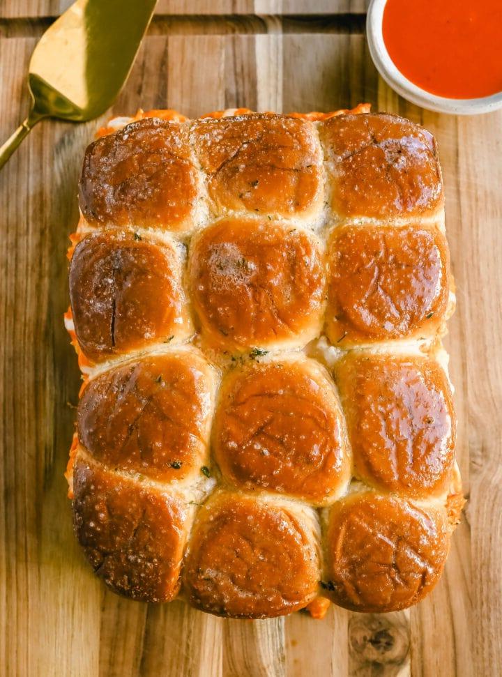 Οι Sliders Κοτόπουλου Buffalo φτιάχνονται με τρυφερό ψιλοκομμένο κοτόπουλο ανακατεμένο με σάλτσα buffalo και σάλτσα ranch και ψήνονται μέσα σε ένα μαλακό ψωμάκι με βούτυρο σκόρδου και λιωμένο τυρί μοτσαρέλα. Είναι ιδανικά για να παρακολουθήσετε ποδόσφαιρο!