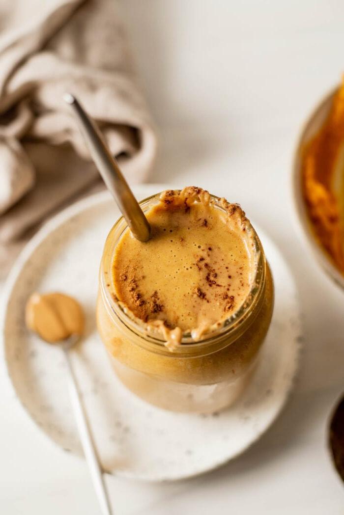 Grondboontjiebotter Pampoen Smoothy 2 Oorhoofse skoot van 'n pampoen smoothie in 'n fles. Lepel pynnebotter rus langsaan.