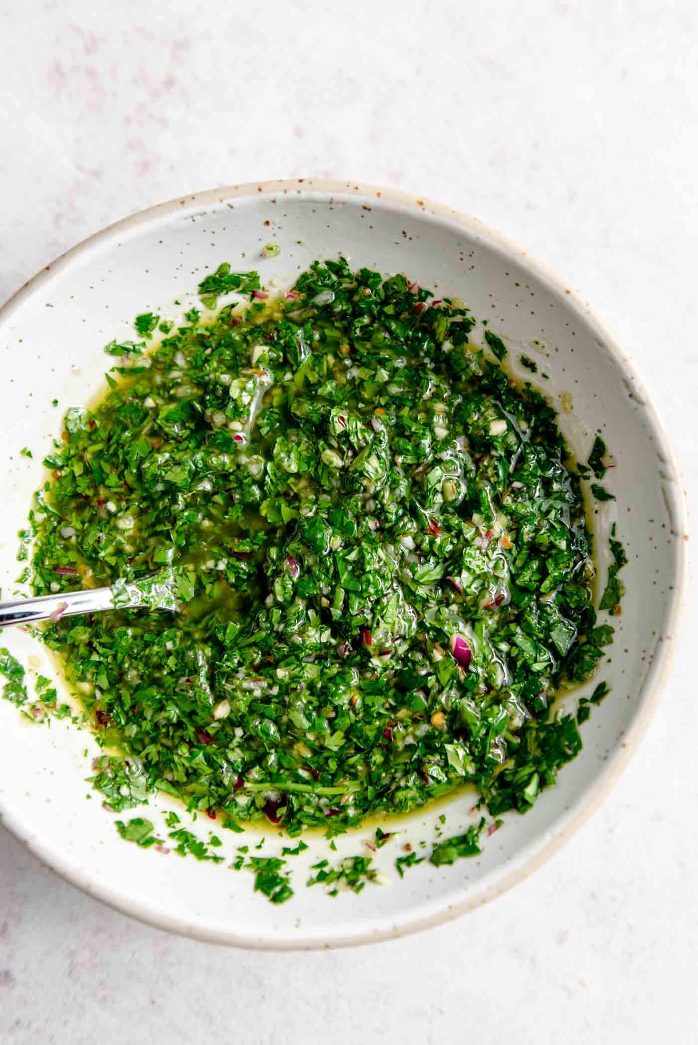 Koriander Tjimmitsjoerri Sous 2 Lewendige groen chimichurri sous in 'n bak met 'n lepel daarin.