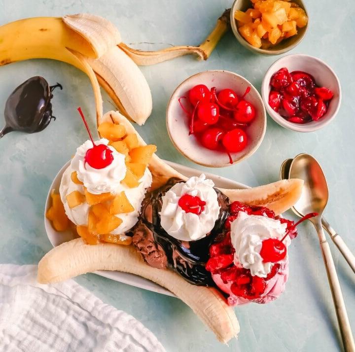 Μπανάνα Σπλιτ 3 Μια κλασική συνταγή για Banana Split φτιαγμένη με φρέσκες μπανάνες, παγωτό σοκολάτα με ζεστή σάλτσα σοκολάτας, παγωτό φράουλα με σάλτσα φράουλας, παγωτό βανίλια με σάλτσα ανανά, σαντιγί και κεράσι.