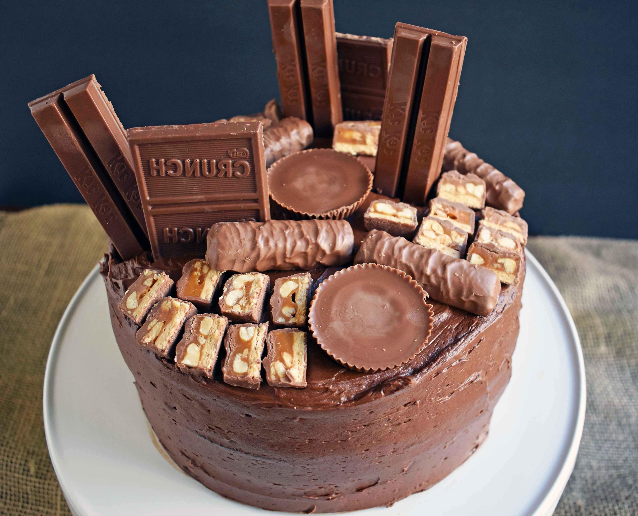 Candy Bar Stash Chocolate Cake by Modern Honey. Perfect chocolate cake topped with chocolate buttercream and the most popular candy bars. It's the ultimate Chocolate Candy Bar Cake.