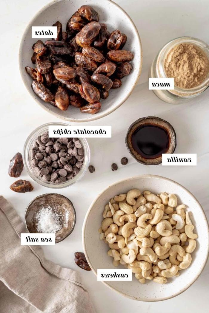 Maca Sjokoladestukkies Energie Balletjies 3 Verskeie bestanddele vir die maak van maca balle, netjies in bakkies gerangskik en duidelik gemerk met teks oorlegsels.