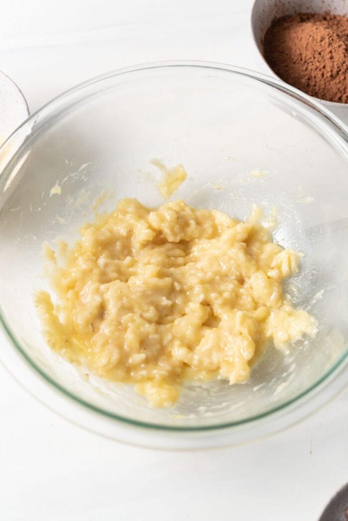 Mashed banana in a glass mixing bowl.