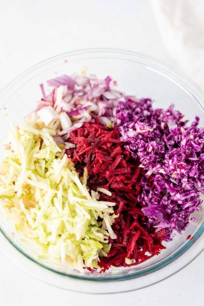 Appel Beet Slaai 4 Gerasperde kool, beet, appel en rooi-ui in 'n mengbak.