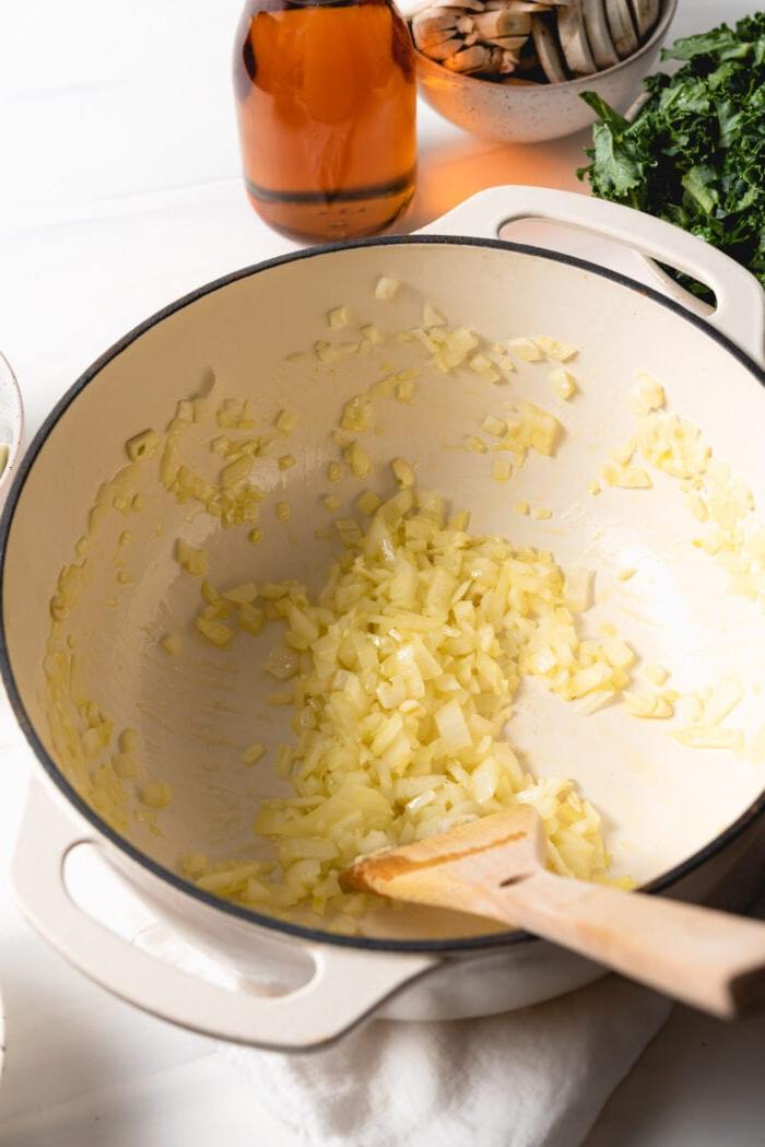 Vegan Een-pot Pasta 4 Chopped onions and garlic cooking in a large pot with a wooden spoon.