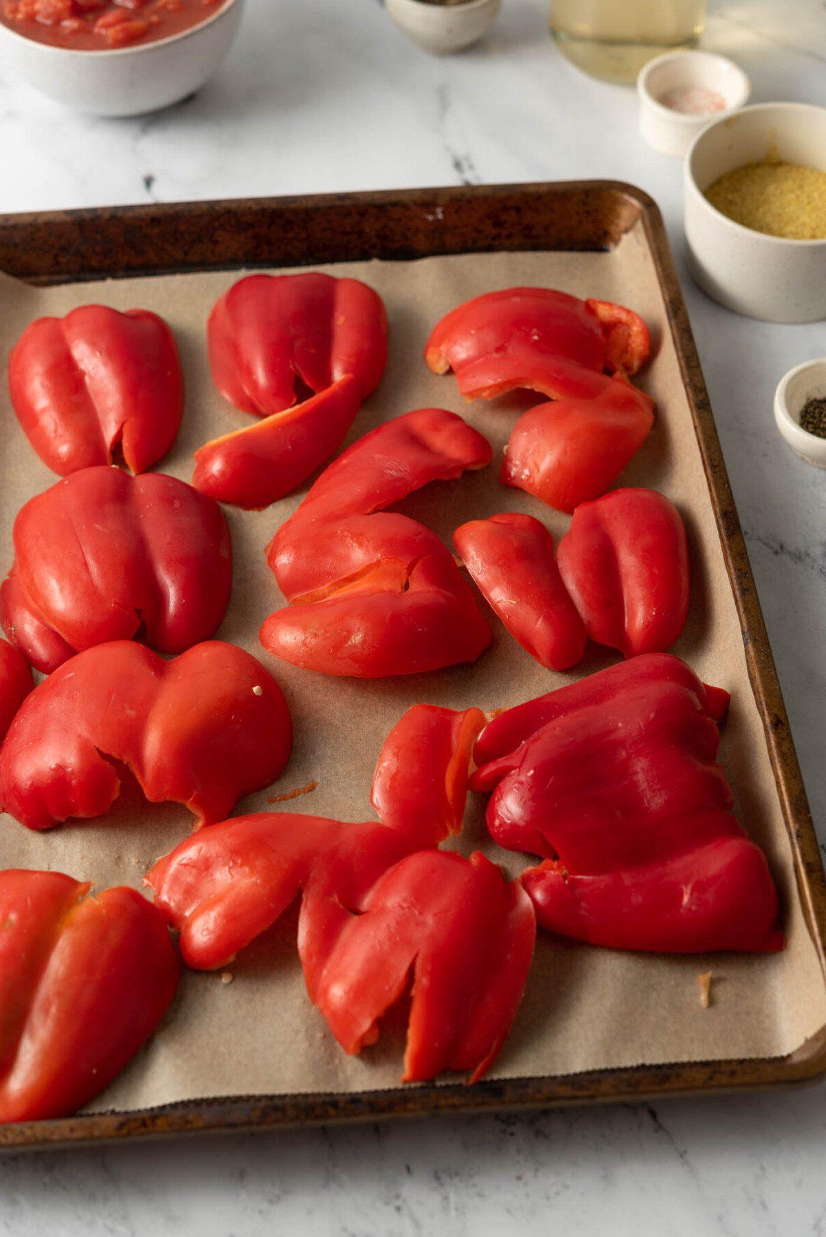 Geroosterde Rooipeper Tamatie Sop 4 Bell peppers smashed down on a baking tray in preparation of making roasted red peppers.