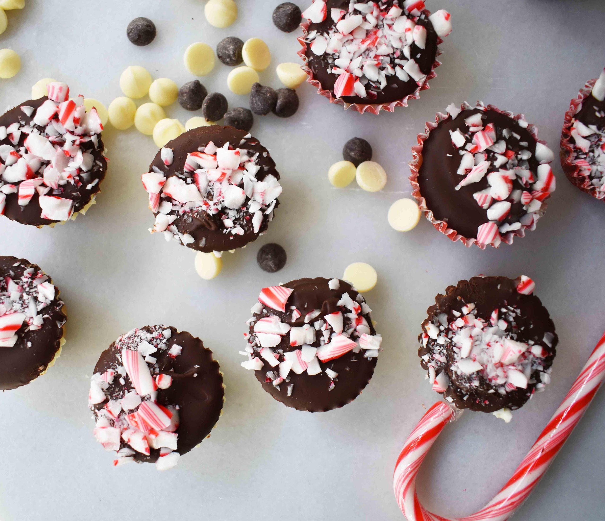 Κυπελλάκια Ζύμης Μπισκότου Peppermint Bark από το Modern Honey. Ζύμη μπισκότου με κομματάκια σοκολάτας χωρίς αυγά, στρωμένη με λευκή σοκολάτα και ημίγλυκη σοκολάτα, και γαρνιρισμένη με τριμμένα ζαχαρωτά μπαστούνια.