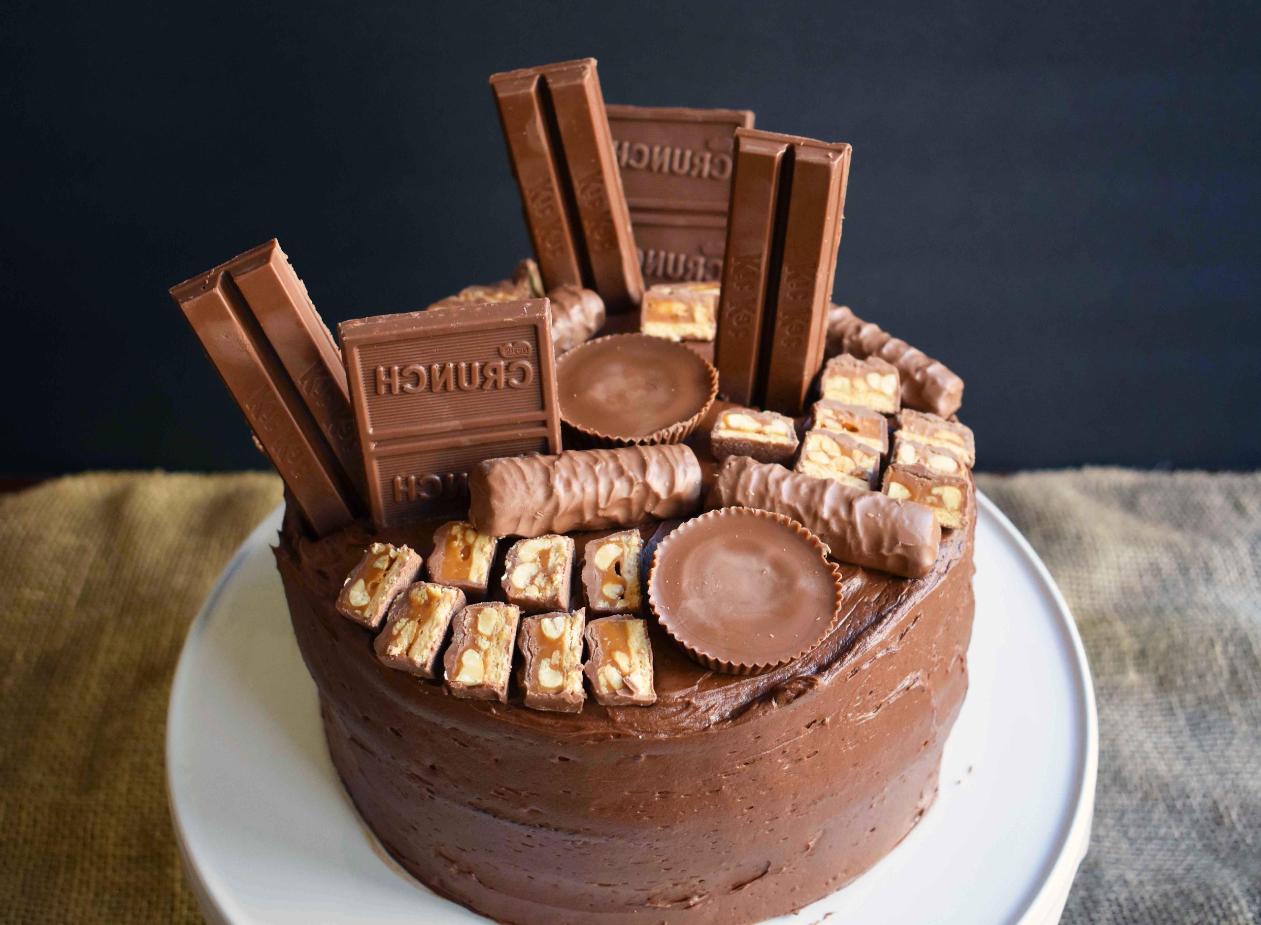 Candy Bar Stash Chocolate Cake by Modern Honey. Perfect chocolate cake topped with chocolate buttercream and the most popular candy bars. It's the ultimate Chocolate Candy Bar Cake.