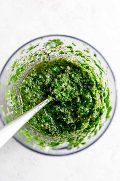 Koriander Tjimmitsjoerri Sous 5 Chimichurri sous in 'n voedselverwerker met 'n lepel daarin.