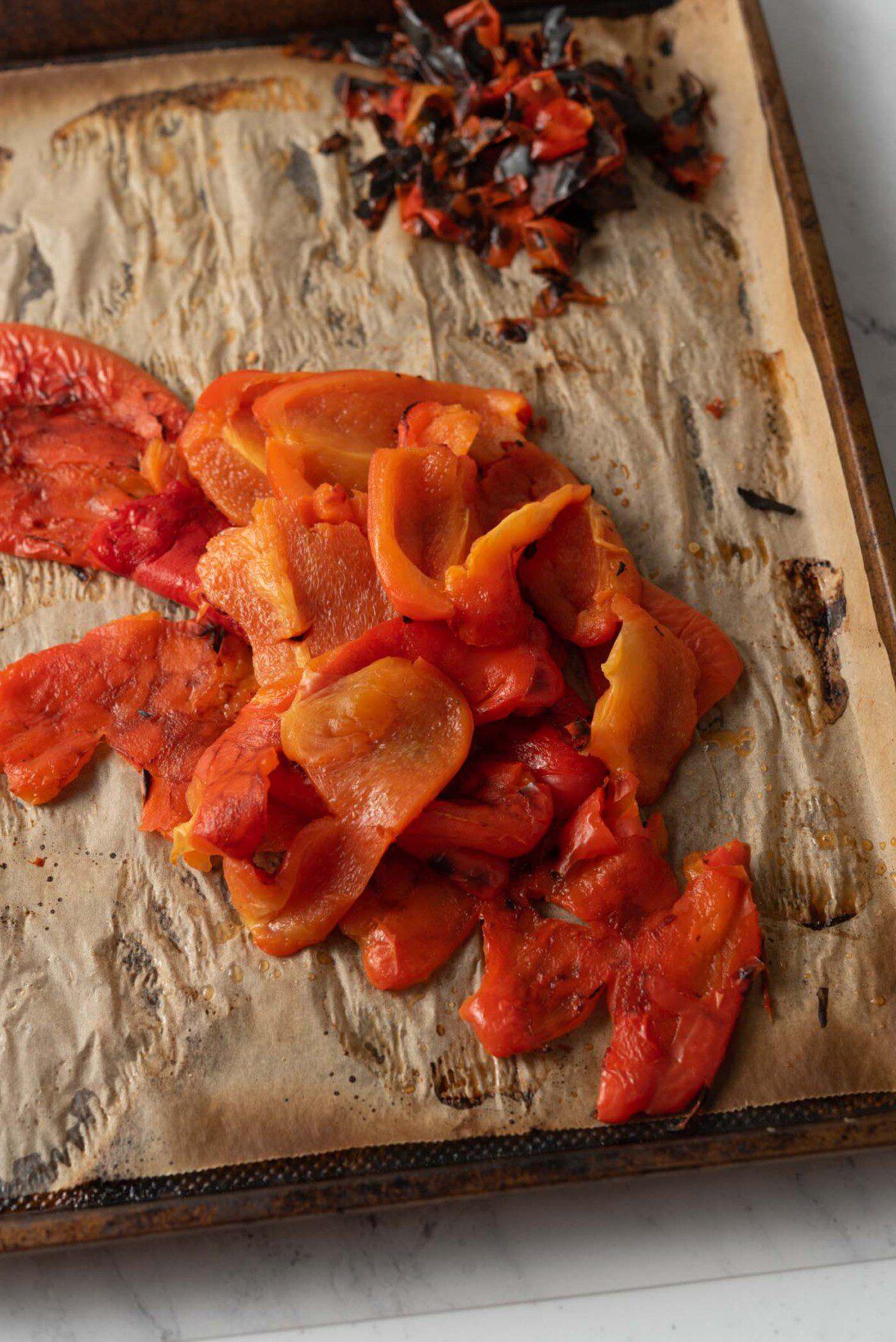 Geroosterde Rooipeper Tamatie Sop 5 Peeled roasted red peppers in a pile on a baking tray.