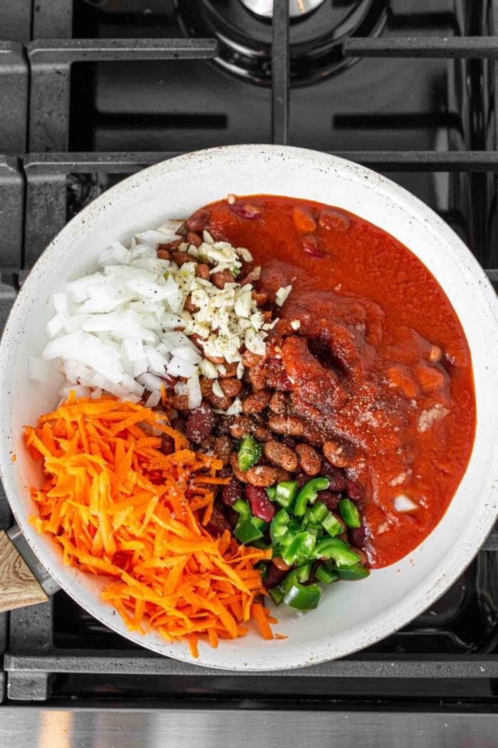 Veganes Chili Kaas Tjips 5 Tamatiesous, groenrissie, ui, wortel en boontjies in 'n pan.