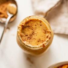 Grondboontjiebotter Pampoen Smoothy 6 Oorhoofse skoot van 'n pampoen smoothie in 'n fles. Lepel pynnebotter rus langsaan.