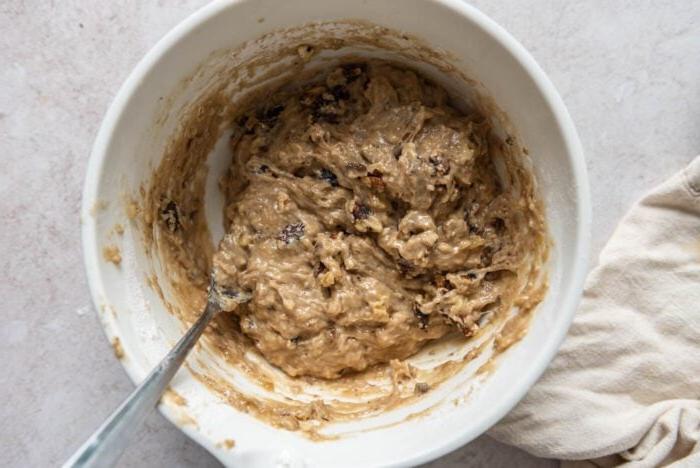 Eierlose Piesangmuffins 6 Piesang-okkerneutmuffinbeslag in 'n mengbak met 'n lepel.