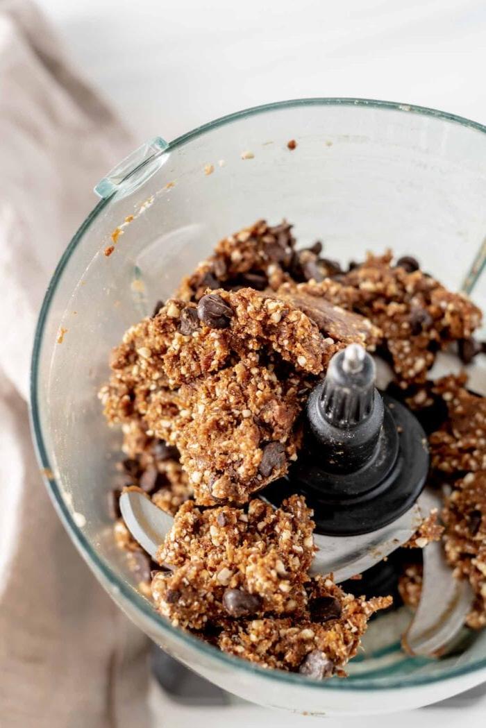 Maca Sjokoladestukkies Energie Balletjies 6 Rou deeg met sjokoladeskyfies in 'n voedselverwerkerhouer, gereed om gerol te word.
