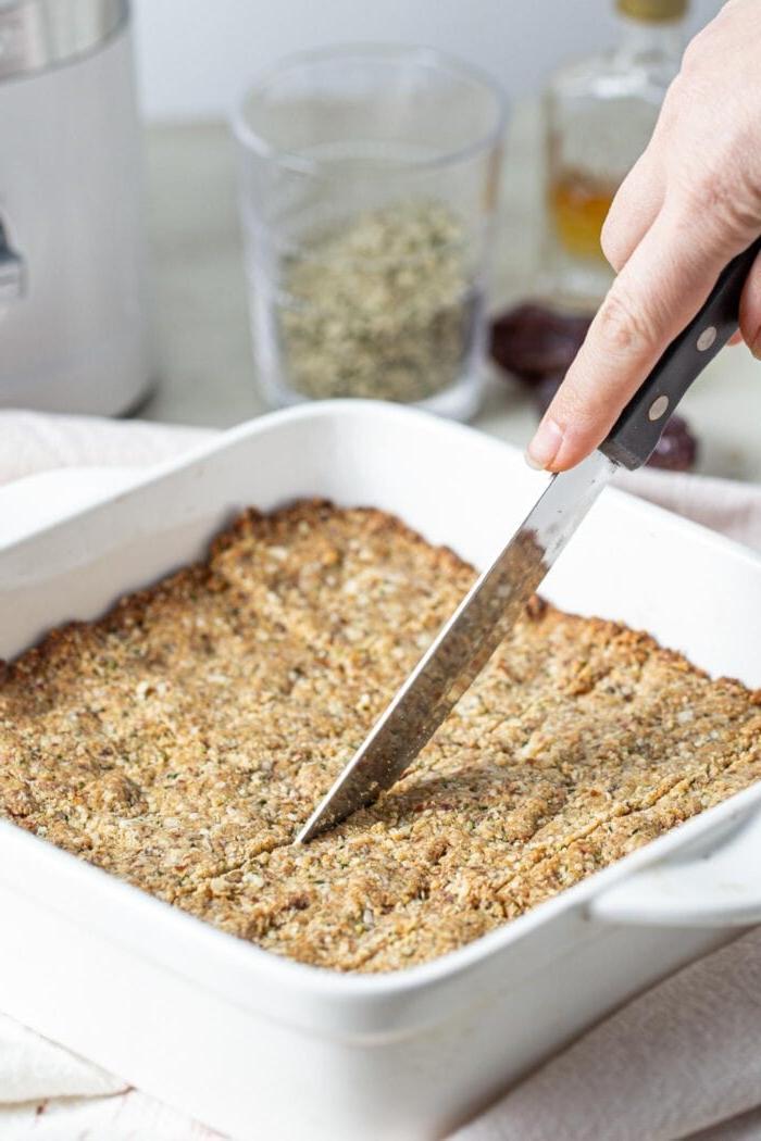 Vegan Tahini Hennepsaad Stafies 6 A knife cutting into bars in a baking dish.