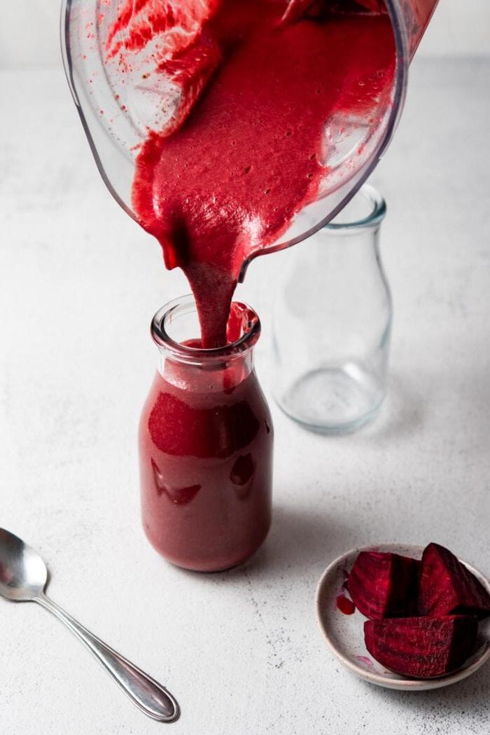 Beet Lemoen Smoothie 6 Pouring a beet smoothie from a blender into a jar.
