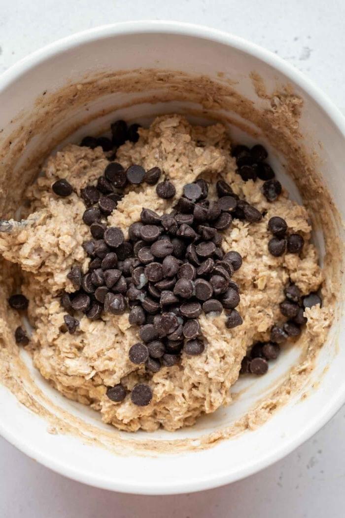Vegan Proteïen Muffins 6 Sjokoladeskyfies wat by 'n mengbak muffinbeslag gevoeg word.
