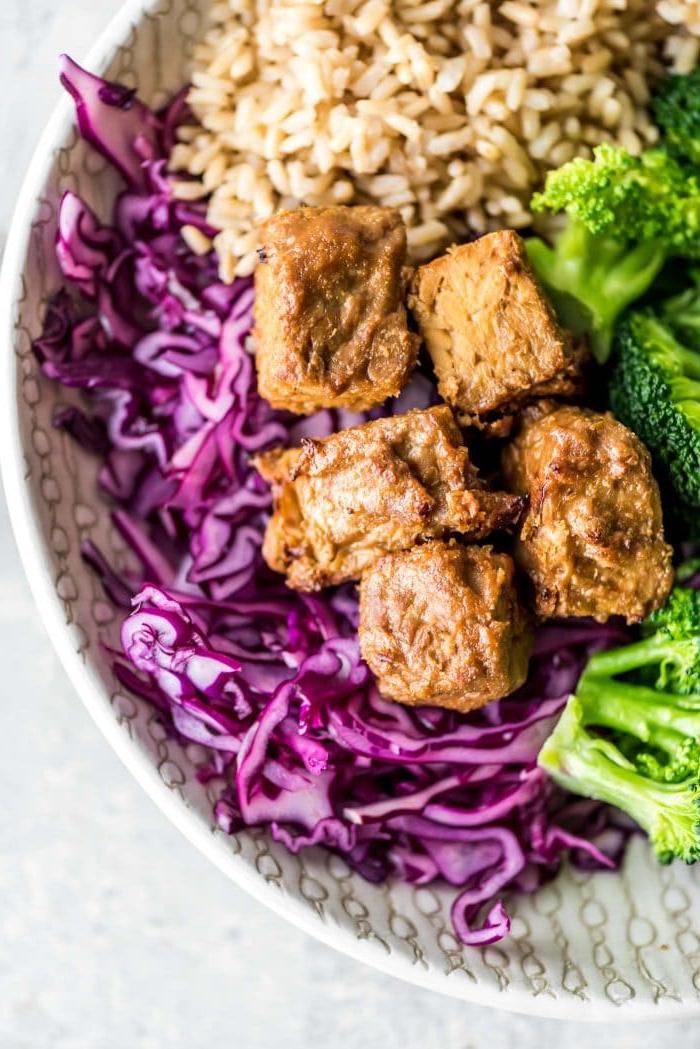 Vegan Makros Eetplanne 5 Gemaalde gebakte tempeh in 'n bak met rooikool, broccoli en bruinrys – 'n volledige en voedsame vegan maaltyd vol proteïen.