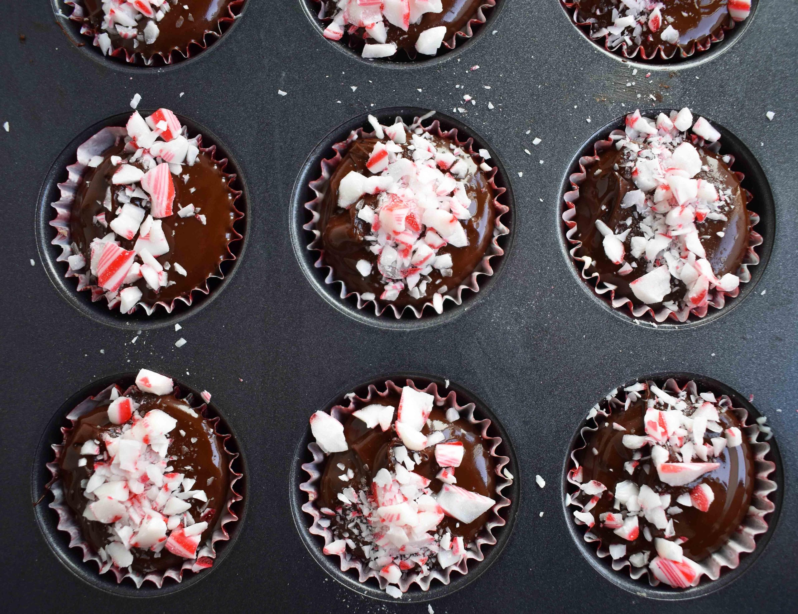 Κυπελλάκια Ζύμης Μπισκότου Peppermint Bark από το Modern Honey. Ζύμη μπισκότου με κομματάκια σοκολάτας χωρίς αυγά, στρωμένη με λευκή σοκολάτα και ημίγλυκη σοκολάτα, και γαρνιρισμένη με τριμμένα ζαχαρωτά μπαστούνια.