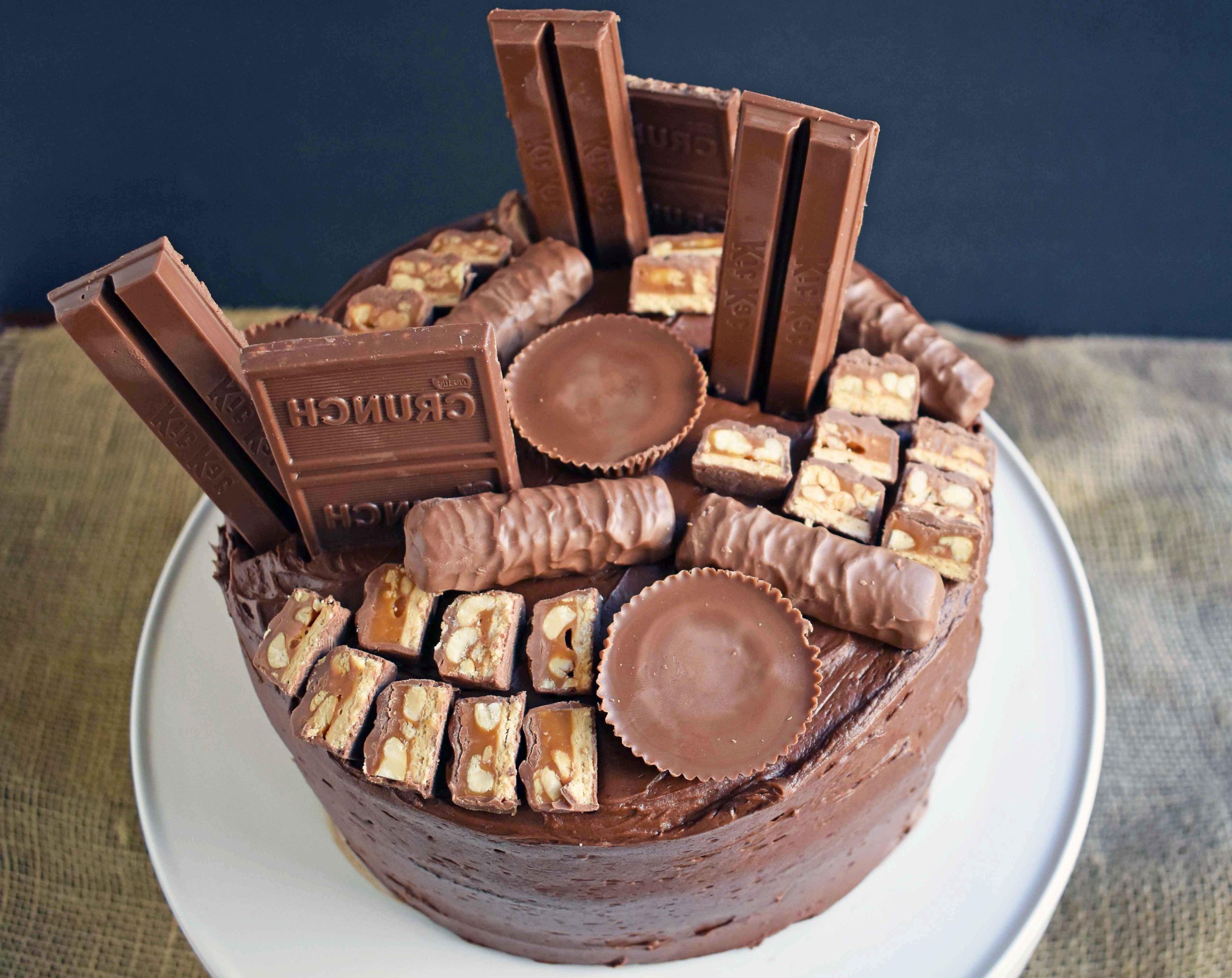 Candy Bar Stash Chocolate Cake by Modern Honey. Perfect chocolate cake topped with chocolate buttercream and the most popular candy bars. It's the ultimate Chocolate Candy Bar Cake.