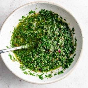 Koriander Tjimmitsjoerri Sous 7 Lewendige groen chimichurri sous in 'n bak met 'n lepel daarin.