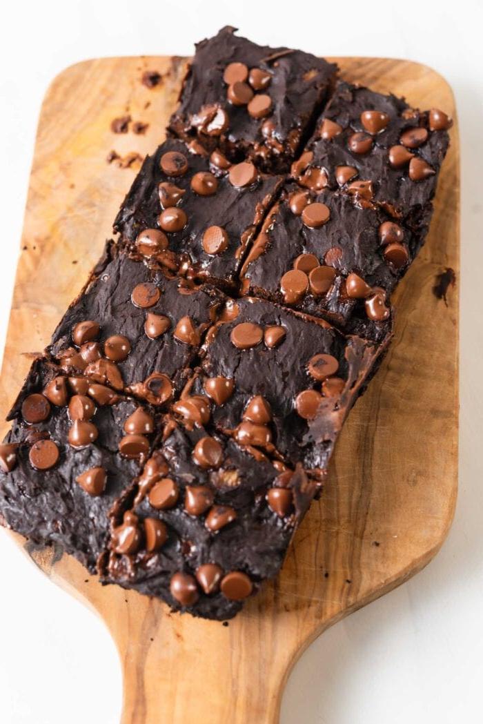 A tray of chocolate chip brownies cut into 8 pieces on a cutting board.