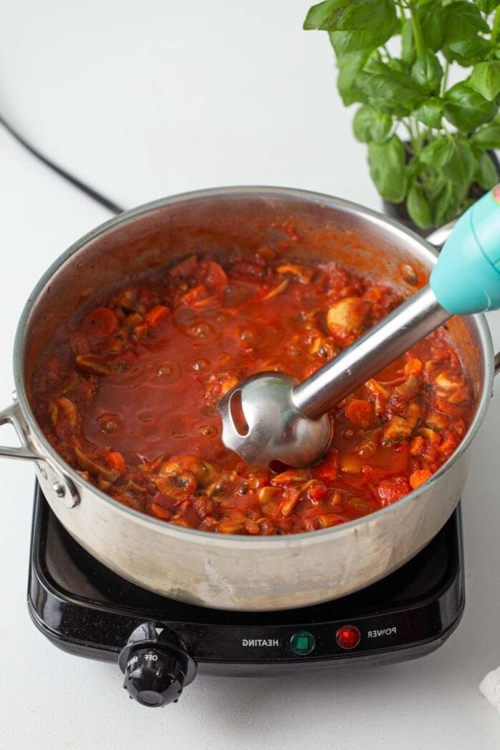 Onderdompelmenger in 'n pot vegan sampioen bolognese sous.
