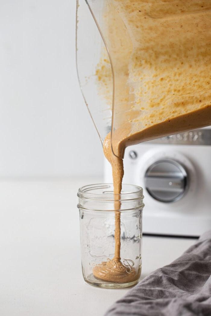 Boerkool Grondboontjie Bruinrys Slaai 7 Blender wat grondboontjiesous in ’n fles uitgooi.