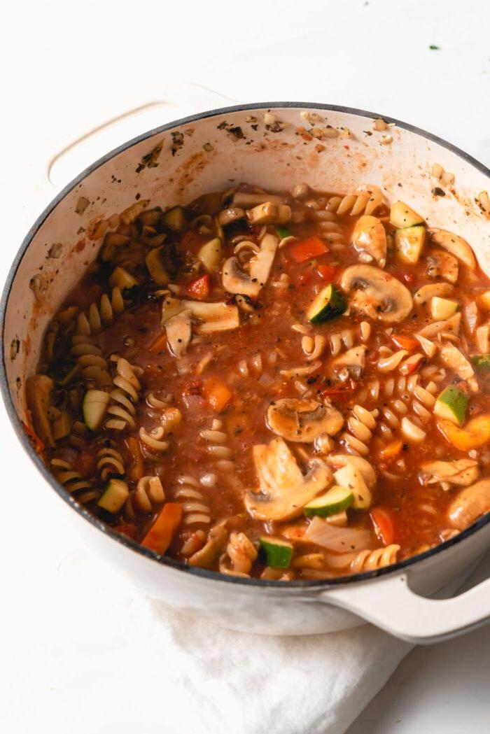Vegan Een-pot Pasta 7 Rotini and vegetables cooking in tomato sauce in a pot.