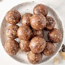 Maca Sjokoladestukkies Energie Balletjies 8 ’n Bo-aansig van ’n bord vol sjokoladeskyfie-energiehappies, pragtig geplaas vir die foto.