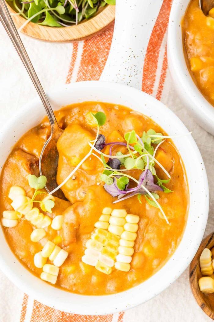 Vegan Somer Mielieroomop 8 Naby-oorsig van 'n bak somerkoringchowder met songedroogde tamatie en aartappel daarin. Die sop is bedek met mieliepitte en 'n paar mikro-groente.