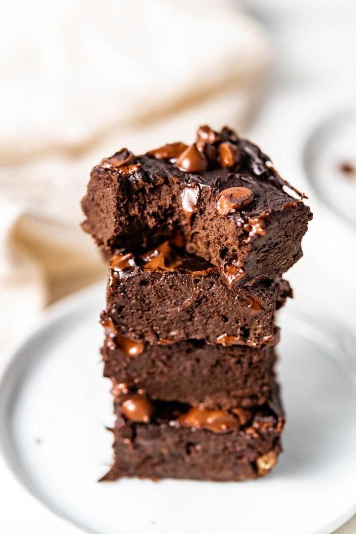 Stack of 4 chocolate brownies with one on top with a bite out of it.