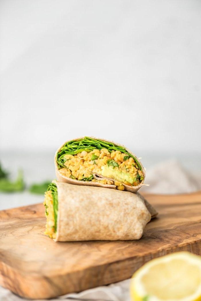 Vegan Makros Eetplanne 7 'n Gemaalde kekerertjie- en spinasie wrap op 'n snyplank – 'n vinnige en proteïenryke vegan middagete of versnapering.