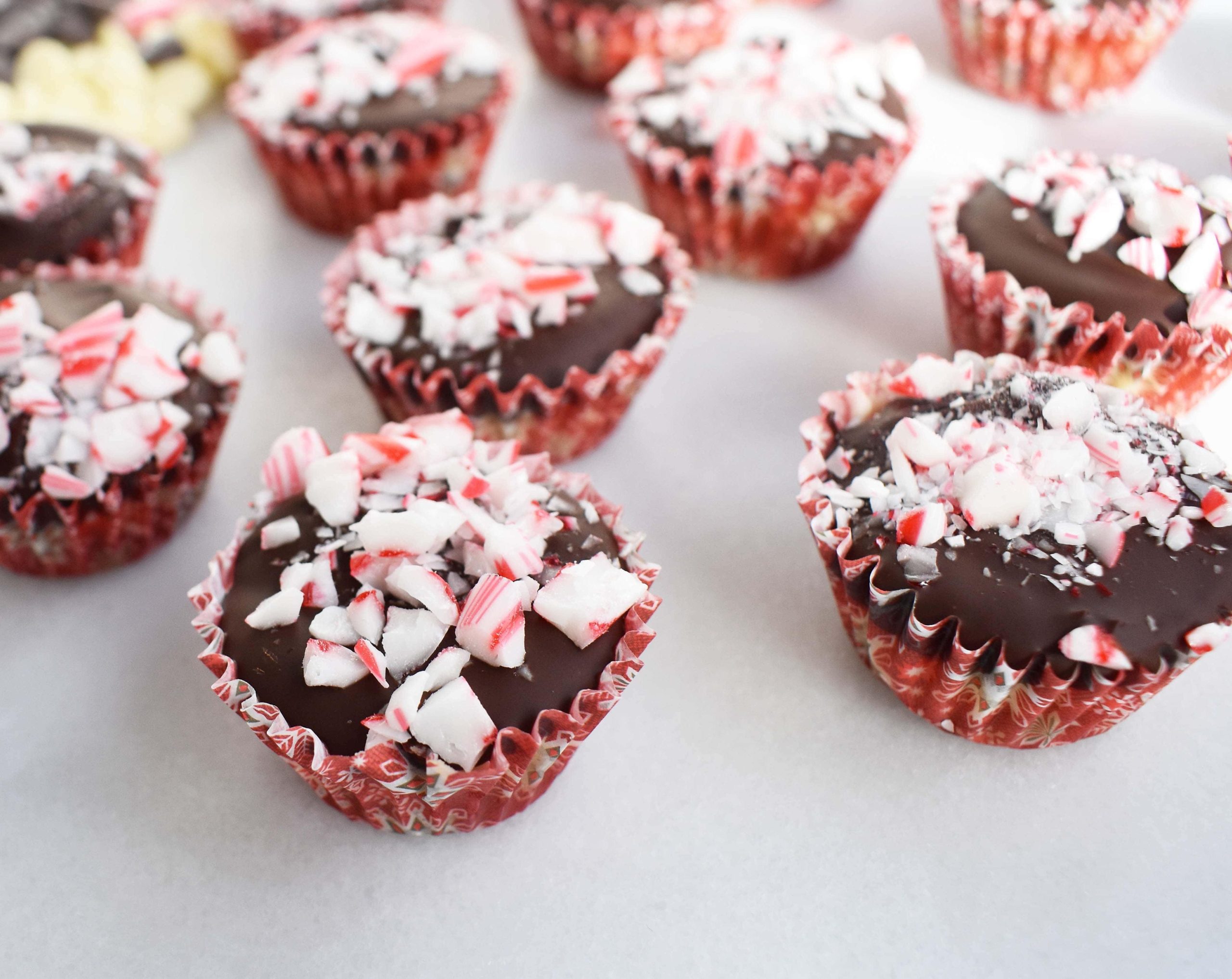 Κυπελλάκια Ζύμης Μπισκότου Peppermint Bark από το Modern Honey. Ζύμη μπισκότου με κομματάκια σοκολάτας χωρίς αυγά, στρωμένη με λευκή σοκολάτα και ημίγλυκη σοκολάτα, και γαρνιρισμένη με τριμμένα ζαχαρωτά μπαστούνια.