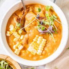 Vegan Somer Mielieroomop 9 Oorsig van 'n bak somerkoringchowder sop bedek met mikro-groente en vars mieliepitte. 'n Lepel rus in die bak en twee addisionele bakke sop is net buite die raam.