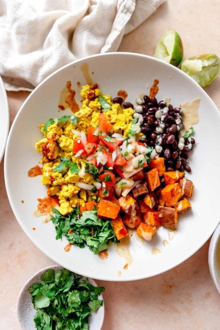 Ontbyt burrito bak met koljander, tofu roereier, swartbone, geroosterde patats, chipotle sous en brandrissiesous oor gestrooi.