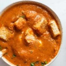 Geroosterde Rooipeper Tamatie Sop 9 Overhead view of a bowl of red pepper tomato soup topped with cubes of toasted bread.