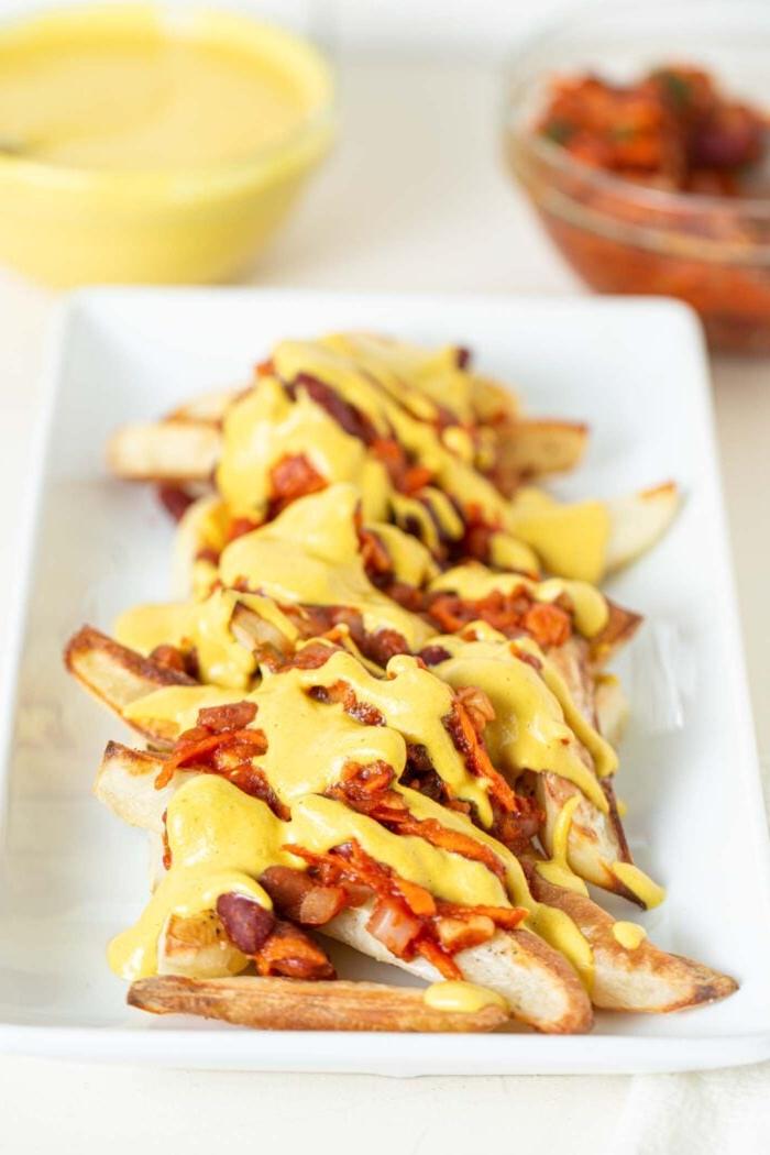 Veganes Chili Kaas Tjips 9 ’n Bord gebakte patatjies bedek met chili en kaassous.