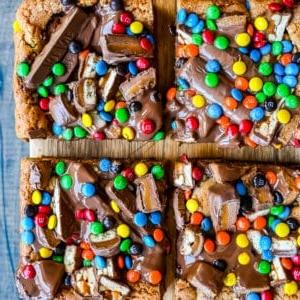 Candy Bar Μπάρες Μπισκότου 10 Μπάρες Μπισκότου με Σοκολάτες. Μια απίστευτα μαλακή και ζουμερή μπάρα μπισκότου, γεμάτη με ποικιλία από σοκολάτες. Το τέλειο γλυκό blondie για να φτιάξετε με τις σοκολάτες του Halloween.