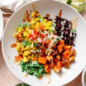 Ontbyt burrito bak met koljander, tofu roereier, swartbone, geroosterde patats, chipotle sous en brandrissiesous oor gestrooi.