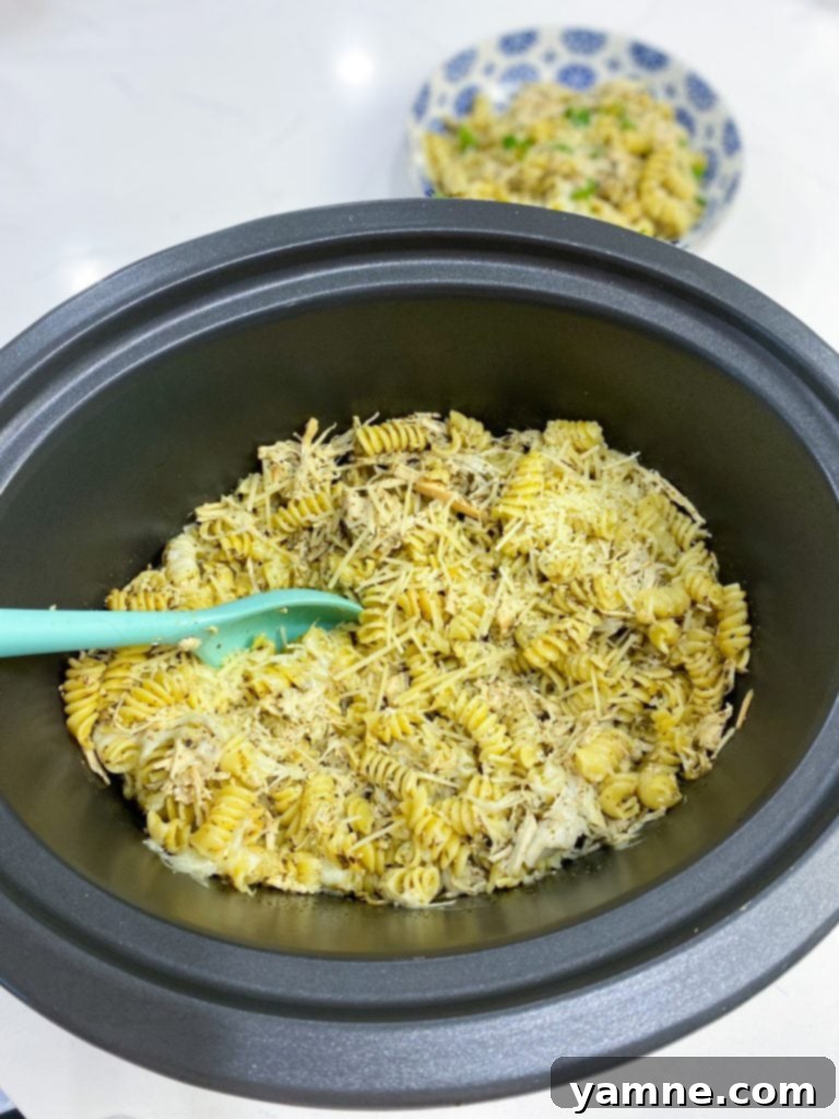 Close-up of Slow Cooker Pesto Chicken Pasta in a bowl, garnished with fresh basil