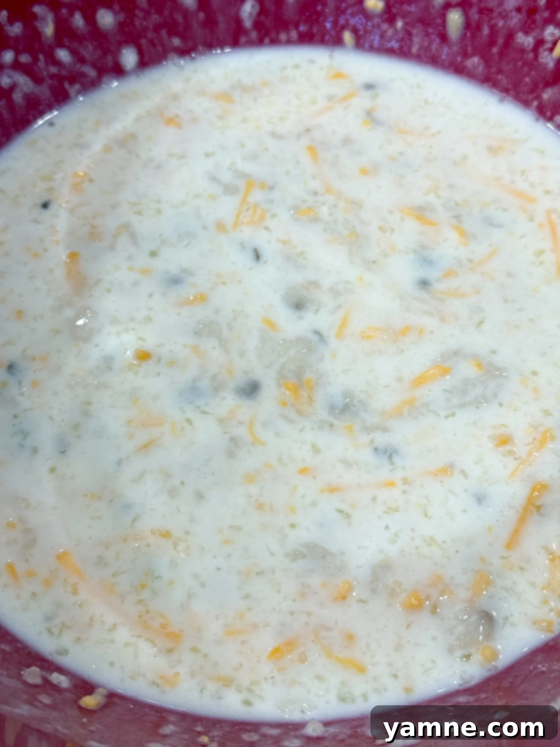 Mixing cream of mushroom soup, milk, and cheese in a bowl
