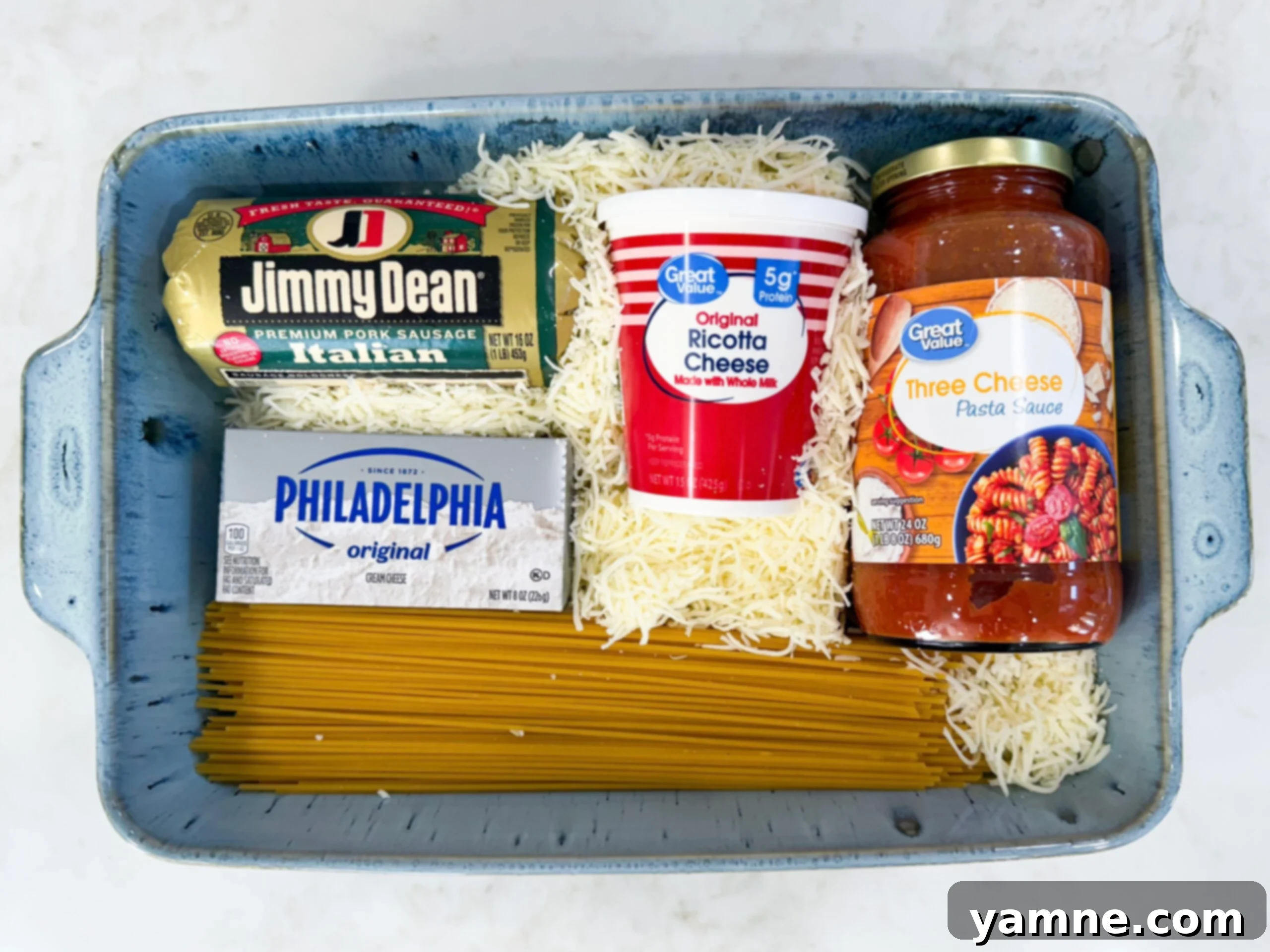 Ingredients for Million Dollar Spaghetti including Italian sausage, cream cheese, ricotta, pasta sauce, mozzarella, and spaghetti noodles.