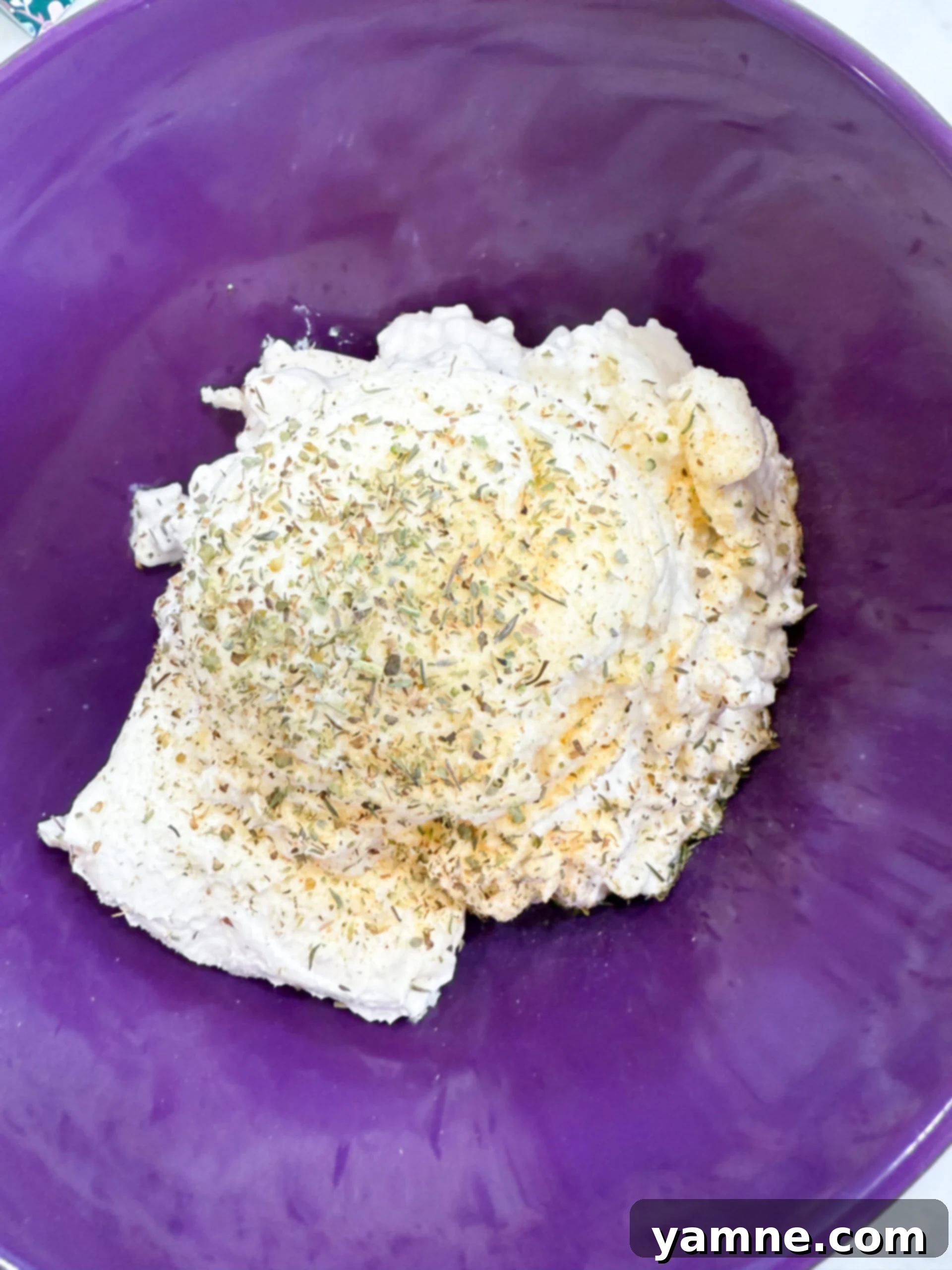 Ricotta, cream cheese, and seasonings blended together in a bowl for the creamy casserole filling.