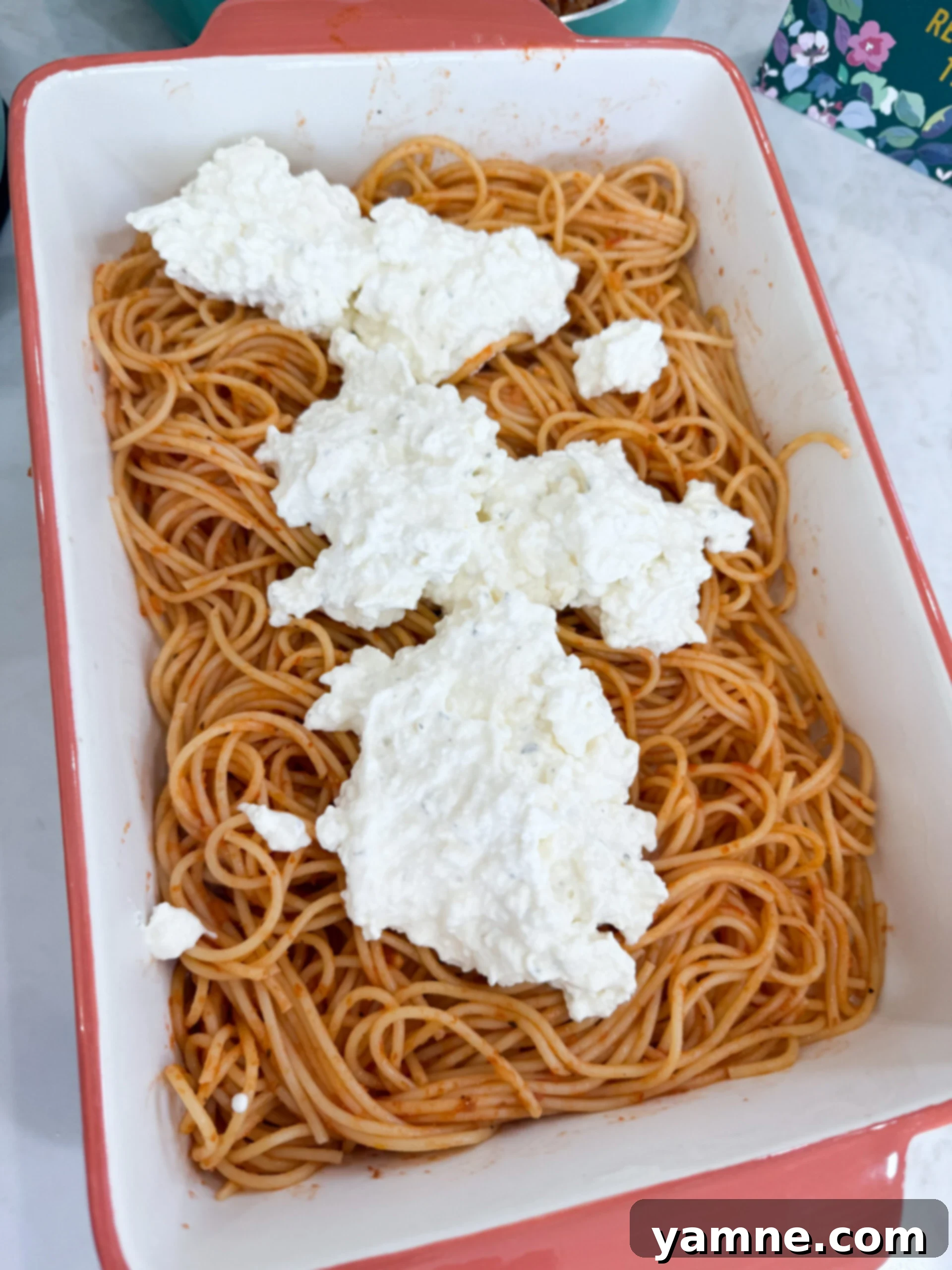 Ricotta and cream cheese mixture spread over spaghetti in the casserole dish.