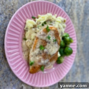 Velvety Garlic Chicken 2 Golden brown chicken breasts drenched in creamy garlic sauce, garnished with fresh herbs.