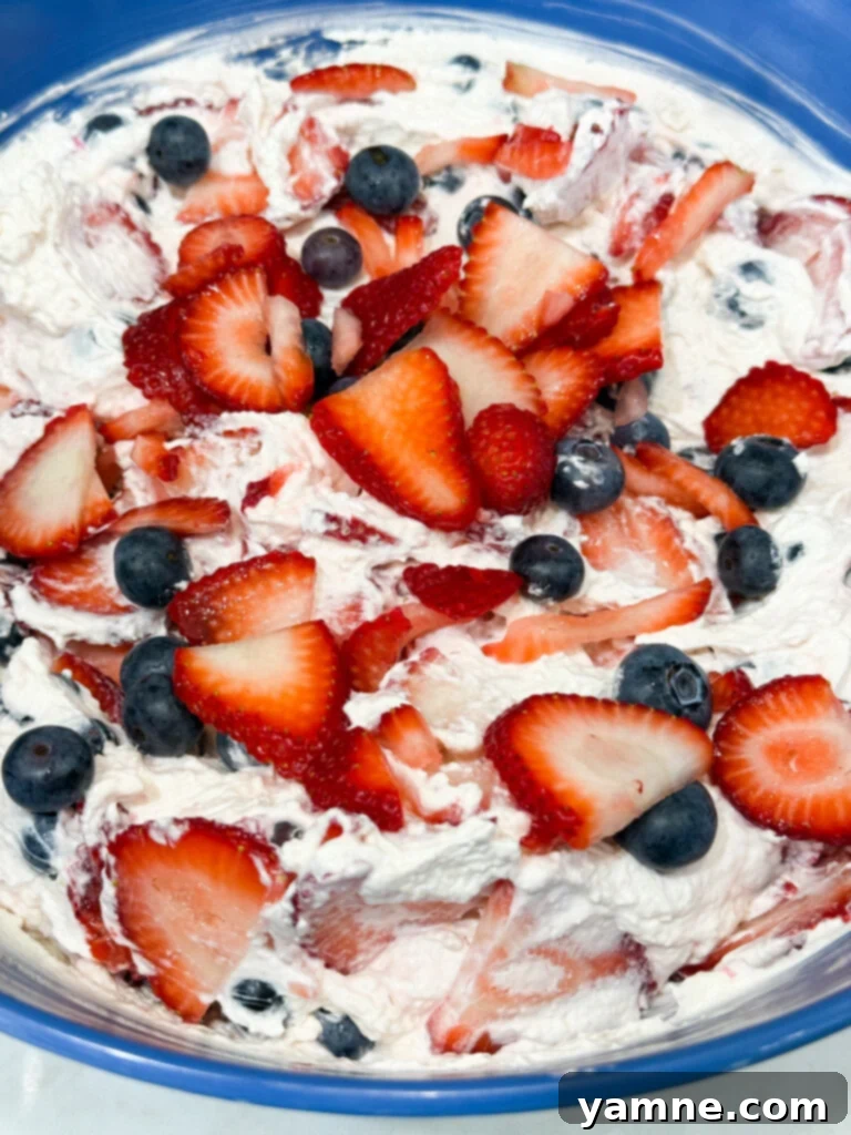 Gently mixing berries into the creamy cheesecake mixture
